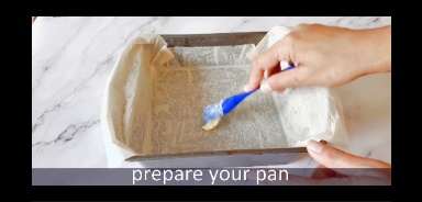 baking pan is coated with butter using blue pastry brush