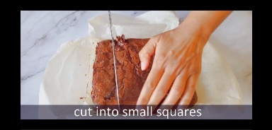 brownies are cut using a knife on parchment paper and marble background