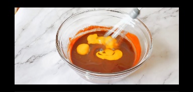 eggs are added to the brownie batter in a glass bowl and mixed using whisk
