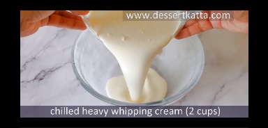 chilled heavy whipping cream is poured in shilled glass bowl