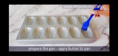 applying butter to the madeleines pan