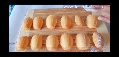 madeleines arranged on wooden board.