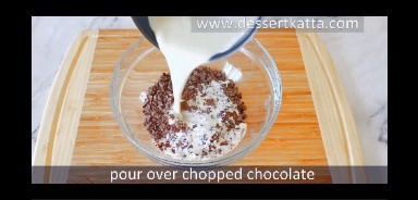 heavy whipping cream is poured over chopped chocolate on wooden board