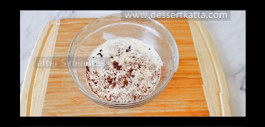 chocolate and heavy cream mixed in a glass bowl and kept over wooden board