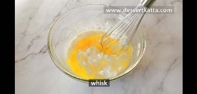 melted butter, oil, milk, sugar, vanilla, eggs, lemon juice, sour cream, and lemon zest is mixed using a whisk in a glass bowl.