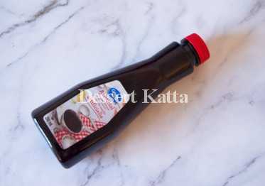 A bottle of artificial vanilla extract is placed on marble