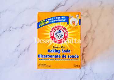 orange box of baking soda placed on marble surface
