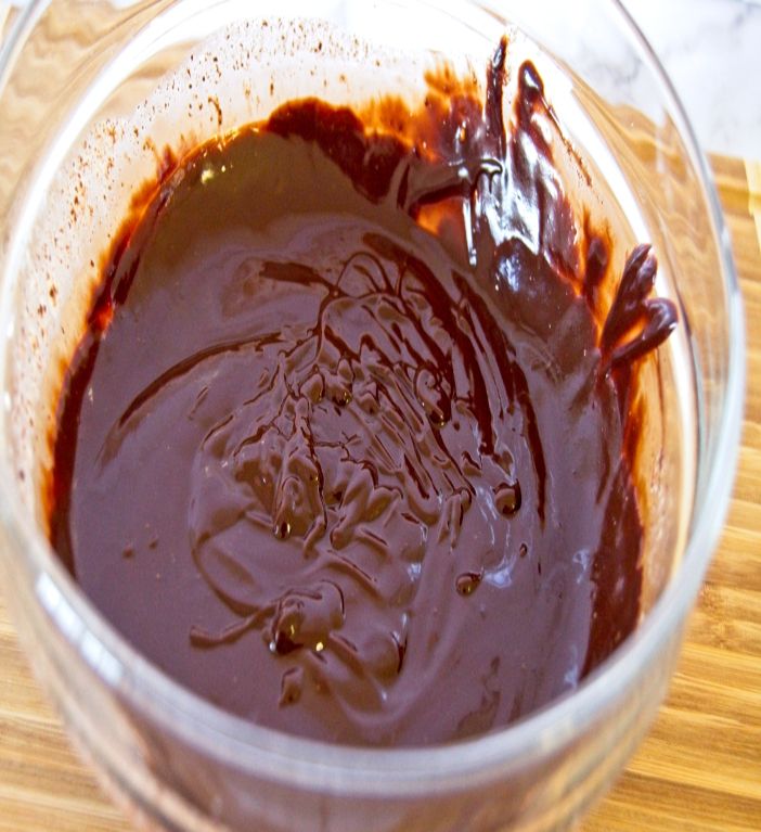 chocolate ganache in a bowl placed on wooden board