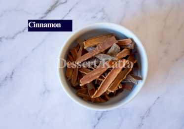 white bowl containing lots of cinnamon sticks and placed on marble surface