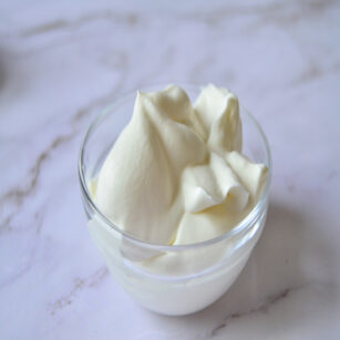 whipped cream placed in small glass bowl on marble surface