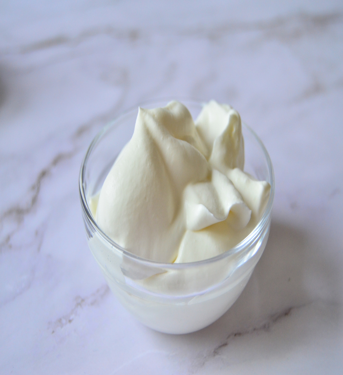 whipped cream placed in small glass bowl on marble surface