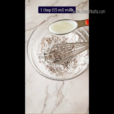 a tablespoon of milk over a glass bowl with other ingredients