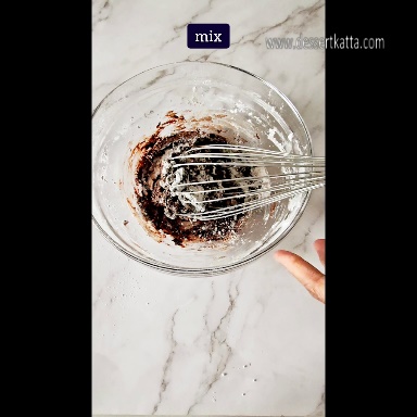 a glass bowl contains ingredients with whisk