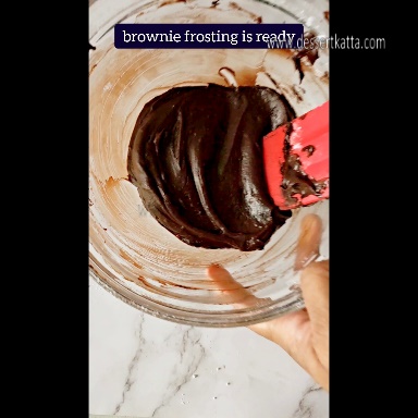 brownie frosting is smoothened with red spatula