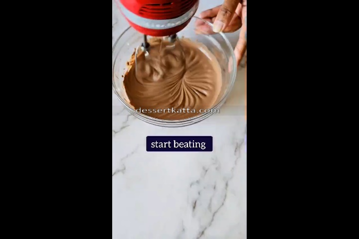 chocolate mousse is beated using hand beater in g glass bowl.