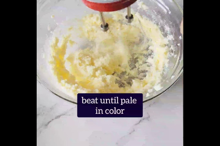 hand beater is beating butter in a glass bowl until pale in color