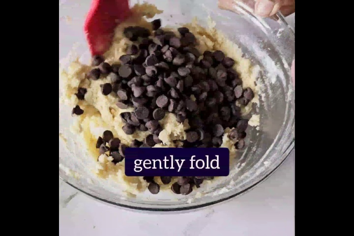 chocolate chips are gently folded in dough with red spatula