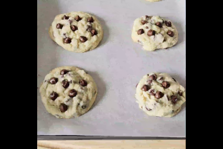 4 no brown sugar cookies are placed on parchment paper with lots of chocolate chips on top