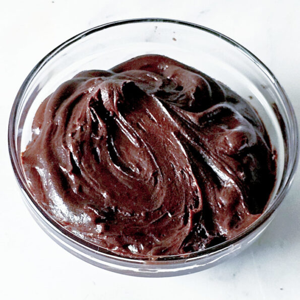 A glass bowl contains decadent chocolate brownie frosting