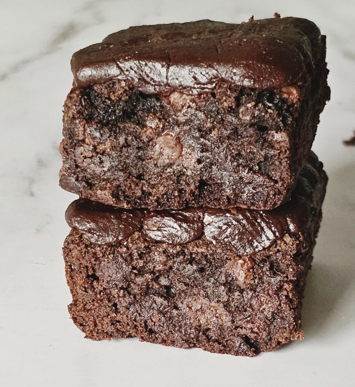 2 brownie pieces frosted with chocolate frosted are stacked