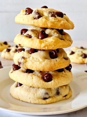 5 no brown sugar cookies are placed on top of each other on white plate with few more cookies in background