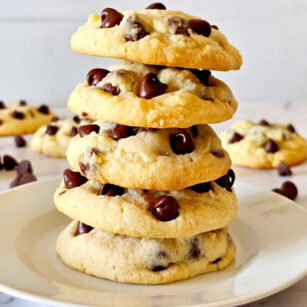 5 no brown sugar cookies are placed on top of each other on white plate with few more cookies in background