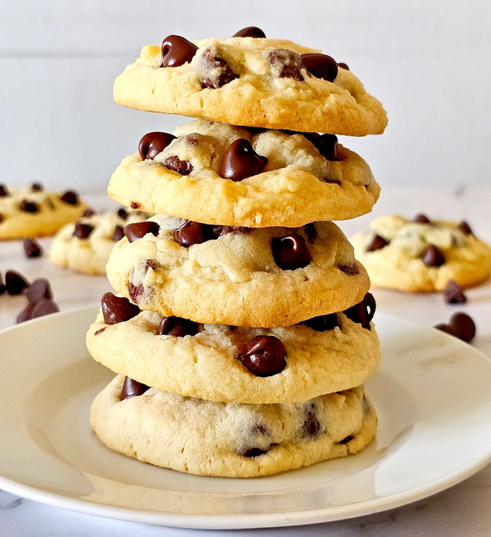 5 no brown sugar cookies are placed on top of each other on white plate with few more cookies in background