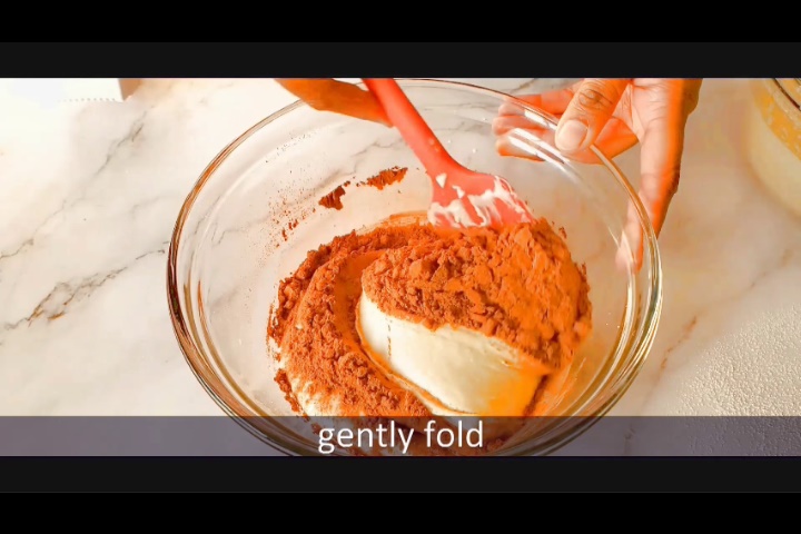 gently folding hersheys cocoa powder using red spatula to make chocolate cake batter