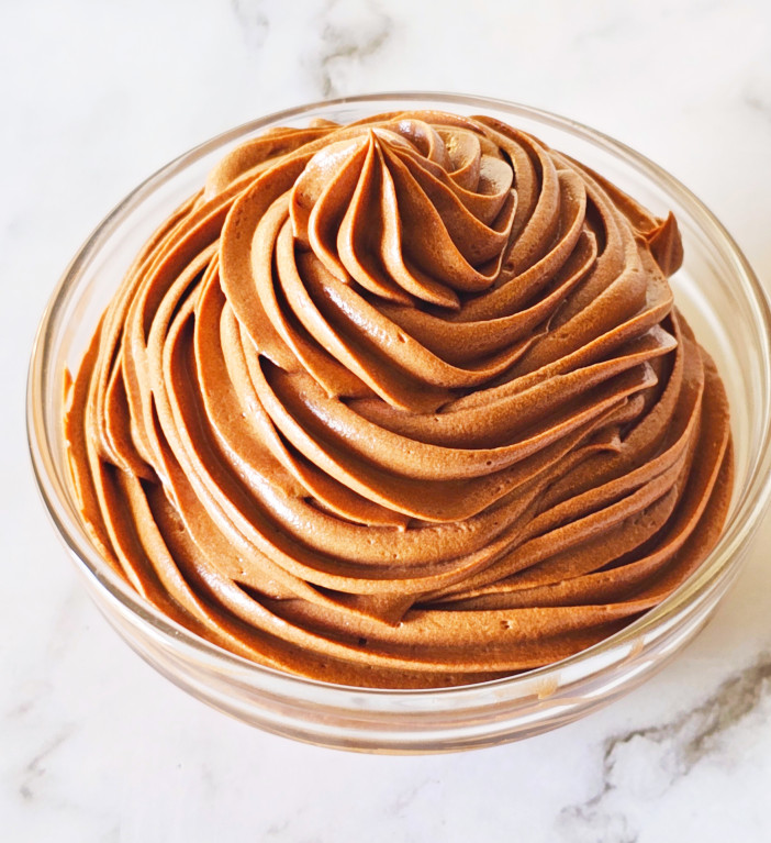 Piped chocolate cream cheese frosting in a small glass bowl