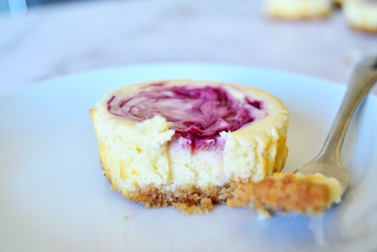 single serving of mini raspberry cheesecakes on white plate and a fork