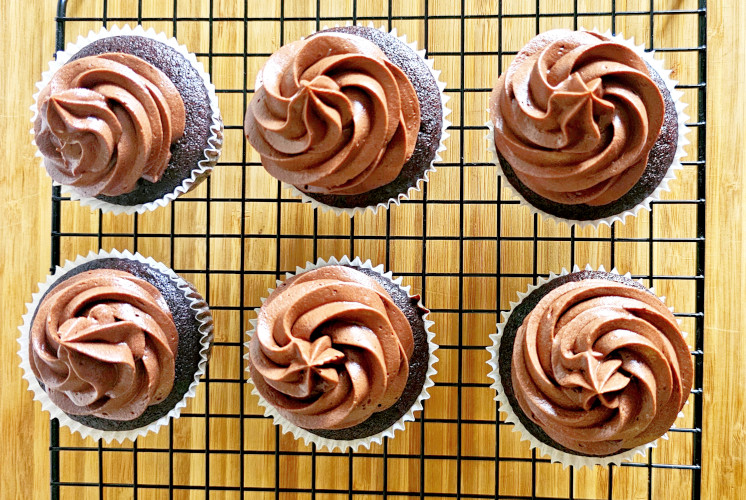 shot of 6 chocolate cupcakes frosted with chocolate cream cheese frosting