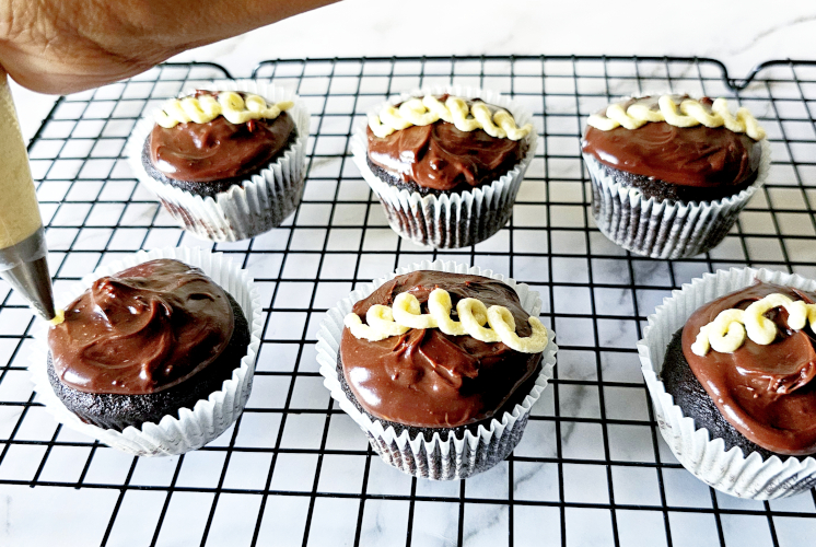 shot of decorating ding dong cupcakes with vanilla icing