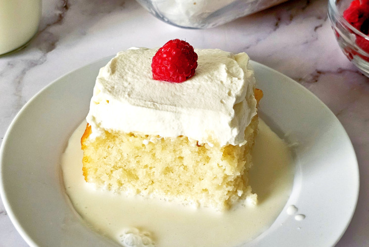 Eggless tres leche piece topped with whipped cream and strawberry