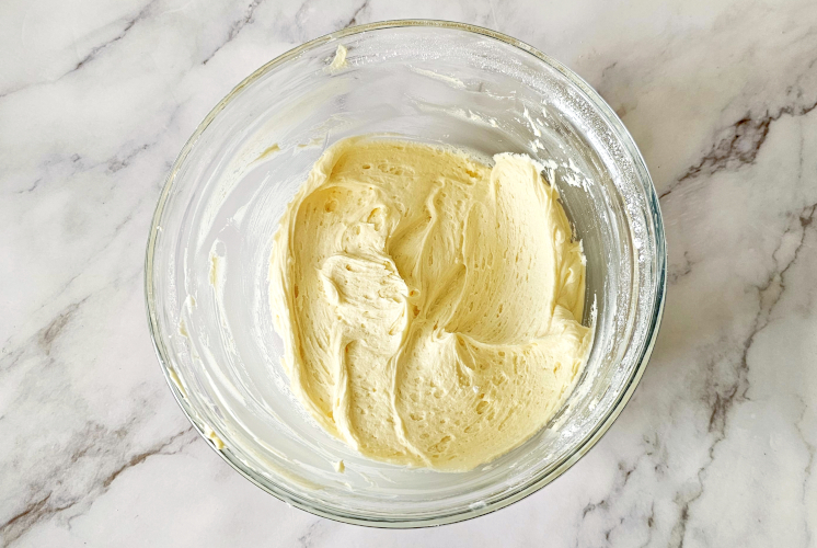 smooth, velvety buttercream in a large mixing bowl placed on marble surface