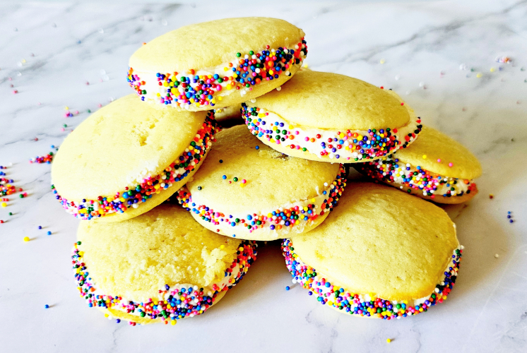 9 individual vanilla whoopie pie are stacked on marble surface