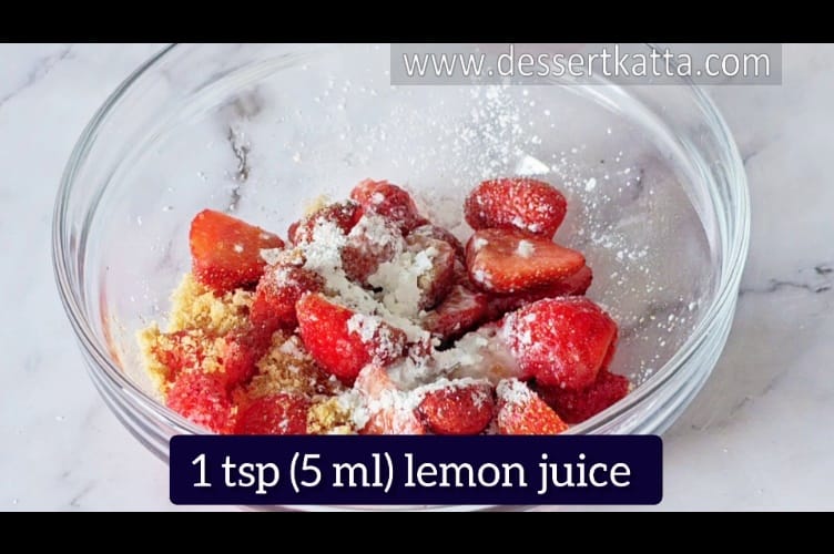 a mixing bowl containing strawberries, sugar and cornstarch to make filling for strawberry crumble