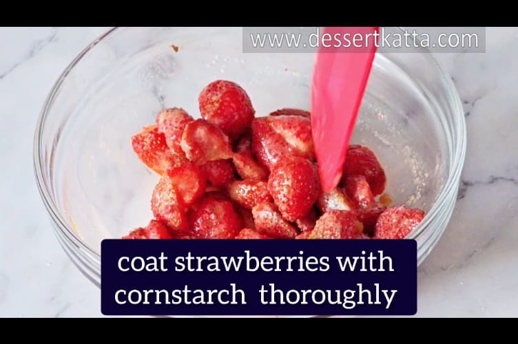 coating strawberries with cornstarch using a red rubber spatula