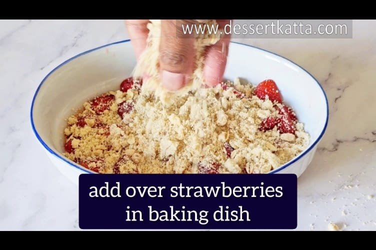 adding crumble topping over strawberry filling