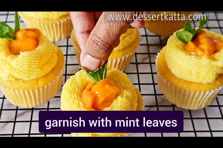 garnishing the cupcakes with mango pieces and mint leave