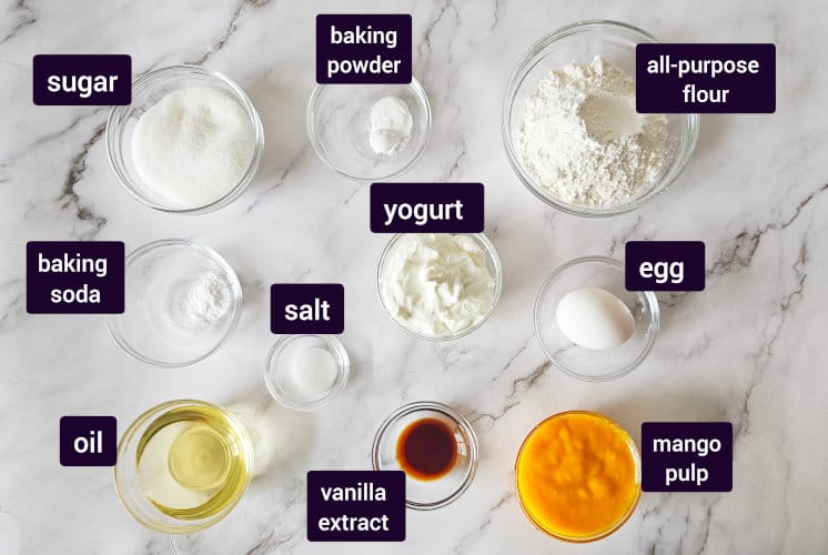 mango cupcake ingredients placed on marble surface in an individual bowls