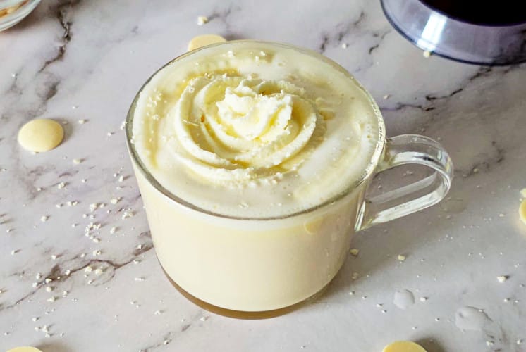 a mug containing white chocolate mocha from starbucks with whipped cream and white chocolate curls on the top